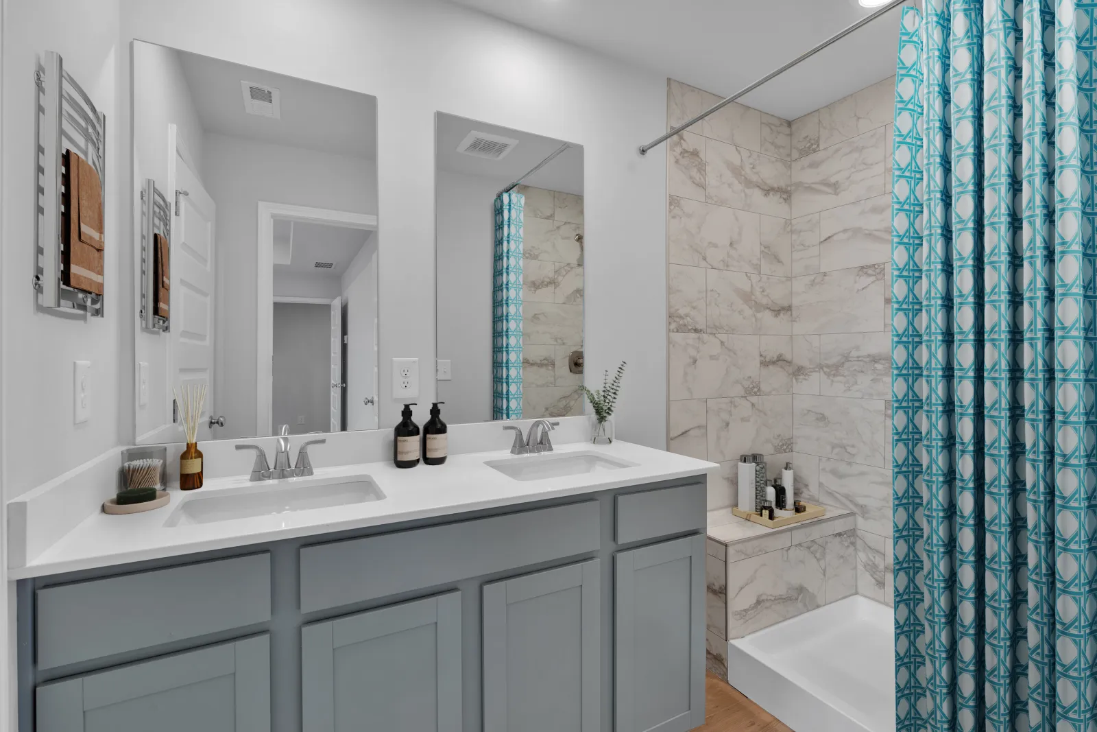 Modern bathroom with double sink vanity, large mirror, marble tiled shower, and teal patterned curtain