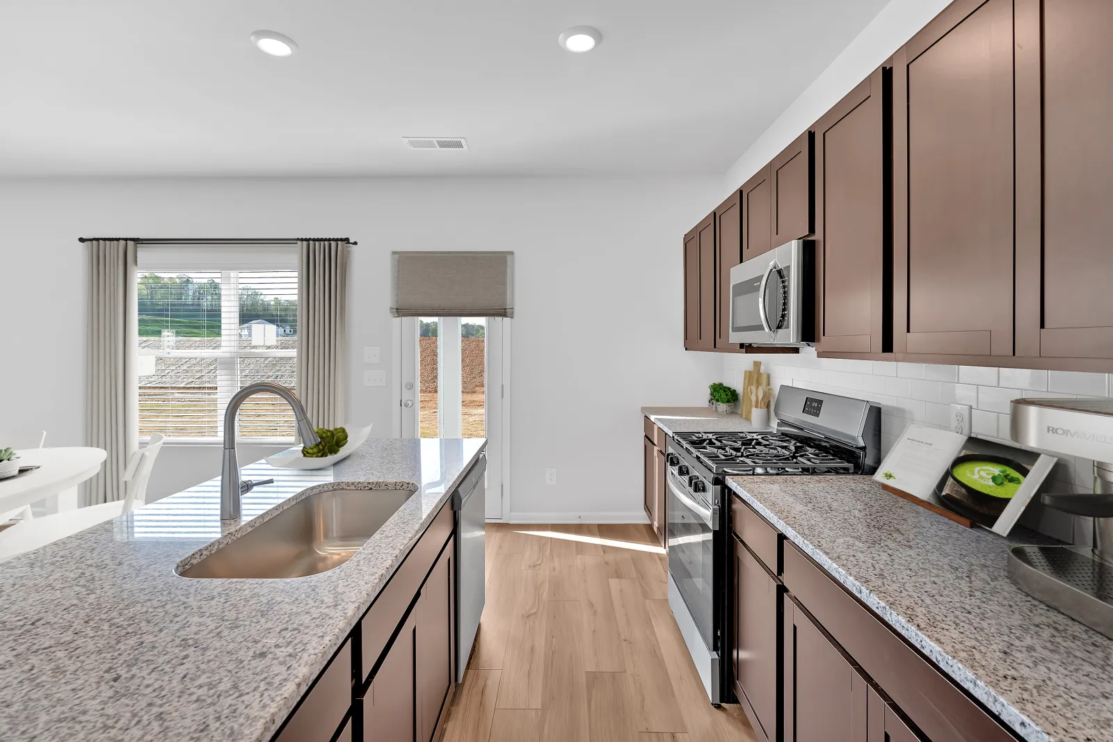 Modern kitchen with granite countertops, stainless steel appliances, and spacious layout in a bright setting.