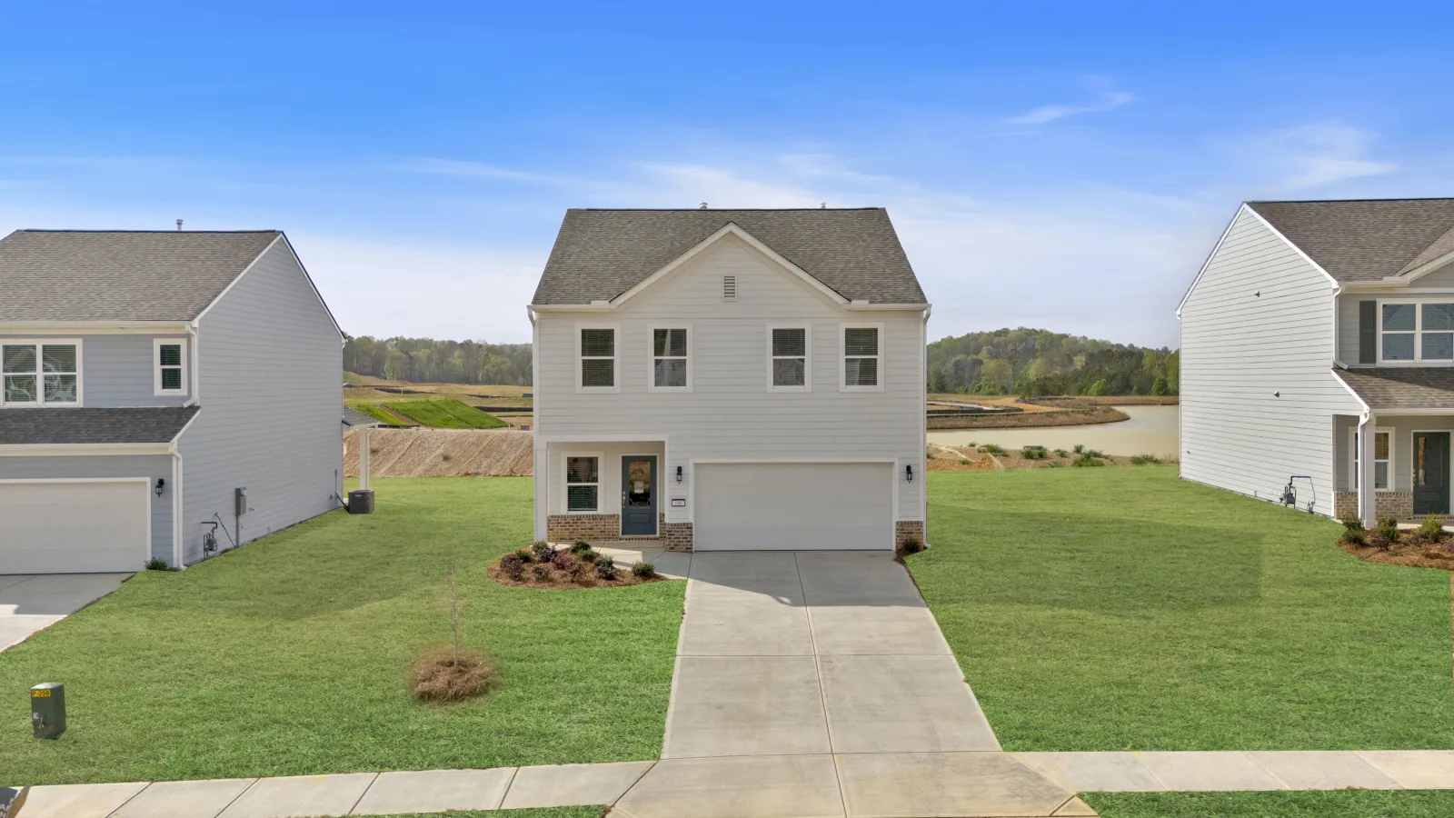 Modern two-story white house with a garage, driveway, and well-kept lawn in a suburban neighborhood.
