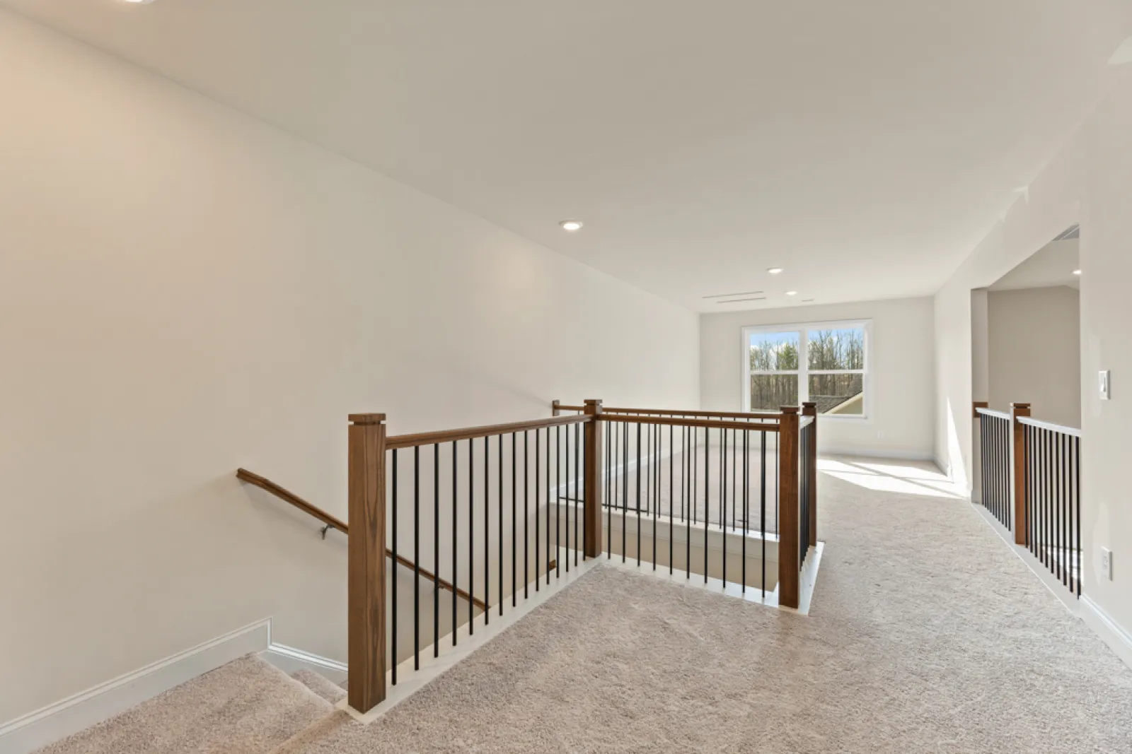 a large white room with a wood railing and a window