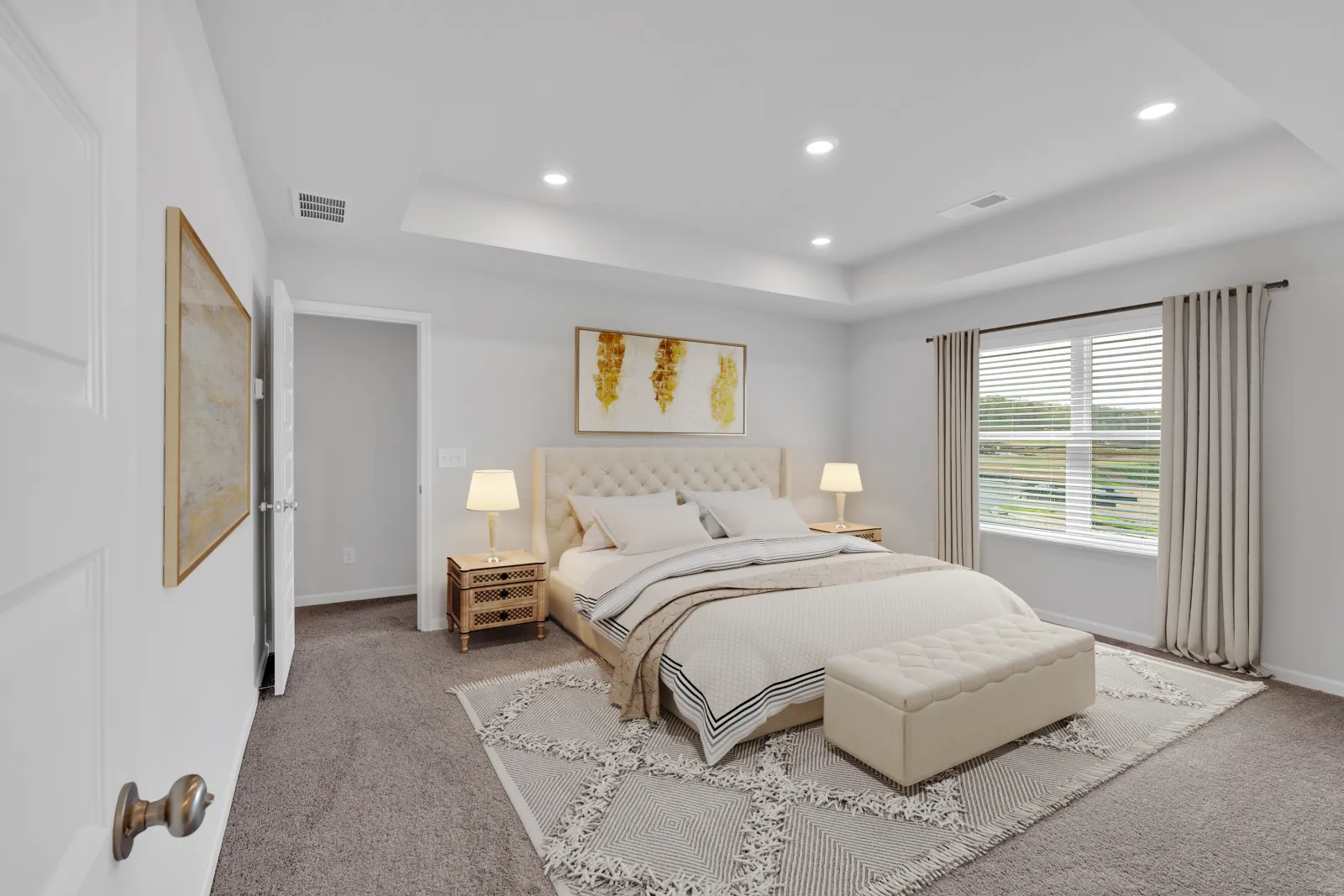 Bright modern bedroom with beige tufted bed, patterned rug, nightstands, lamps, and large window with curtains.