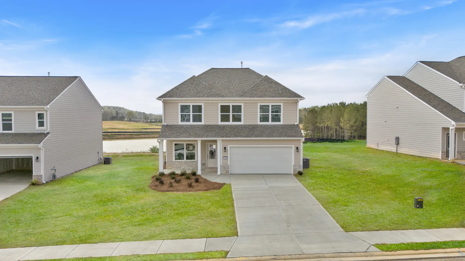 Modern two-story house with gray roof, white siding, and two-car garage on a green lawn under blue sky
