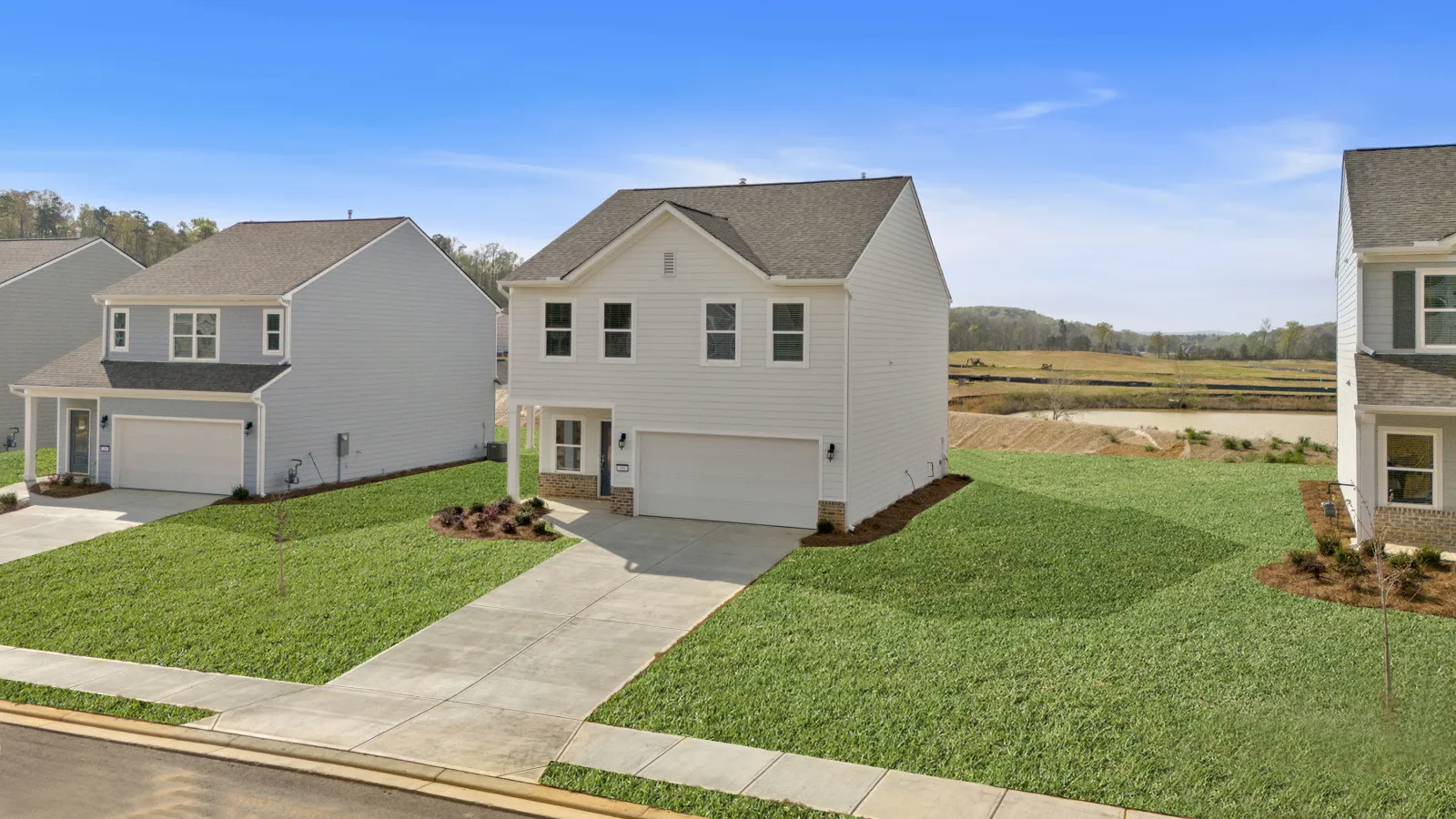 Modern two-story white house with garage and well-kept green lawn in a suburban neighborhood on a clear day