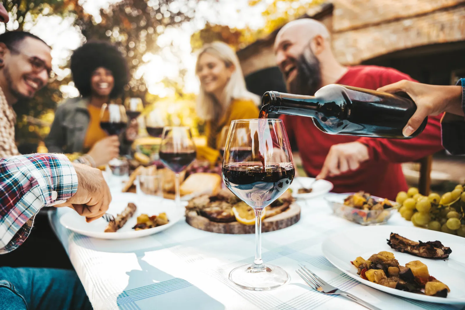 a group of people sitting at a table with food and wine