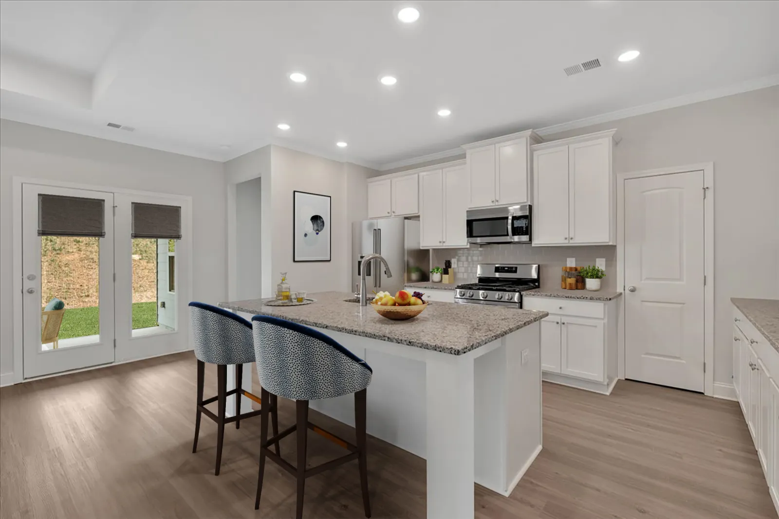 Modern kitchen with granite island, two patterned bar stools, white cabinets, stainless steel appliances, and light wood flooring