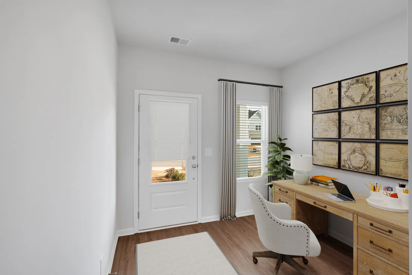 Bright home office with wooden desk, white chair, decorative world map, and a window with gray curtains.