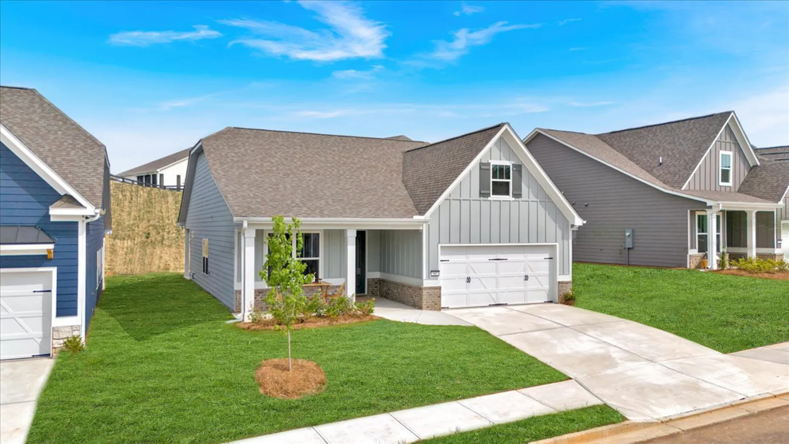 Modern single-story gray house with a two-car garage and green lawn under a blue sky.