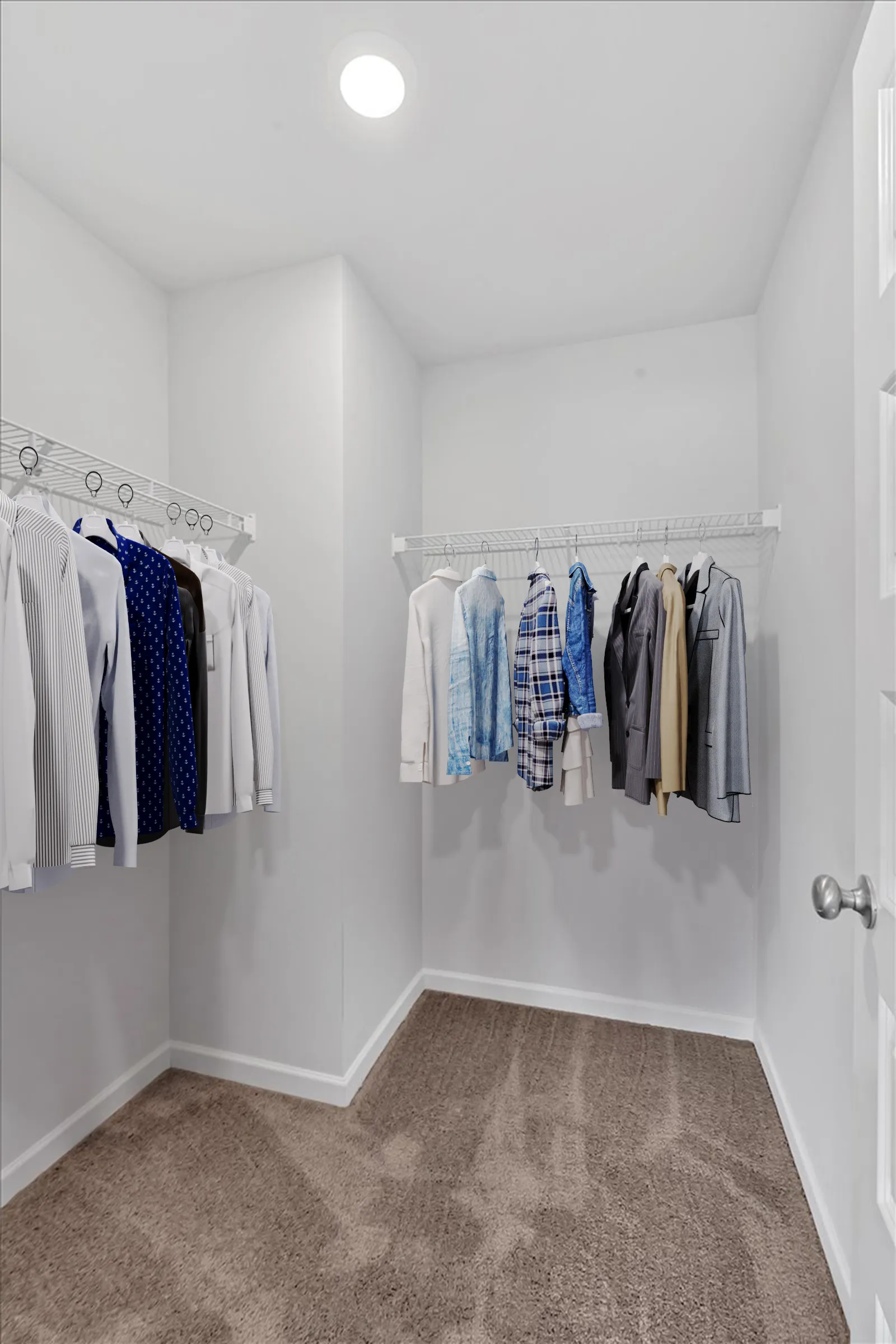 Bright walk-in closet with wire shelving and a variety of hanging shirts and jackets on a carpeted floor.
