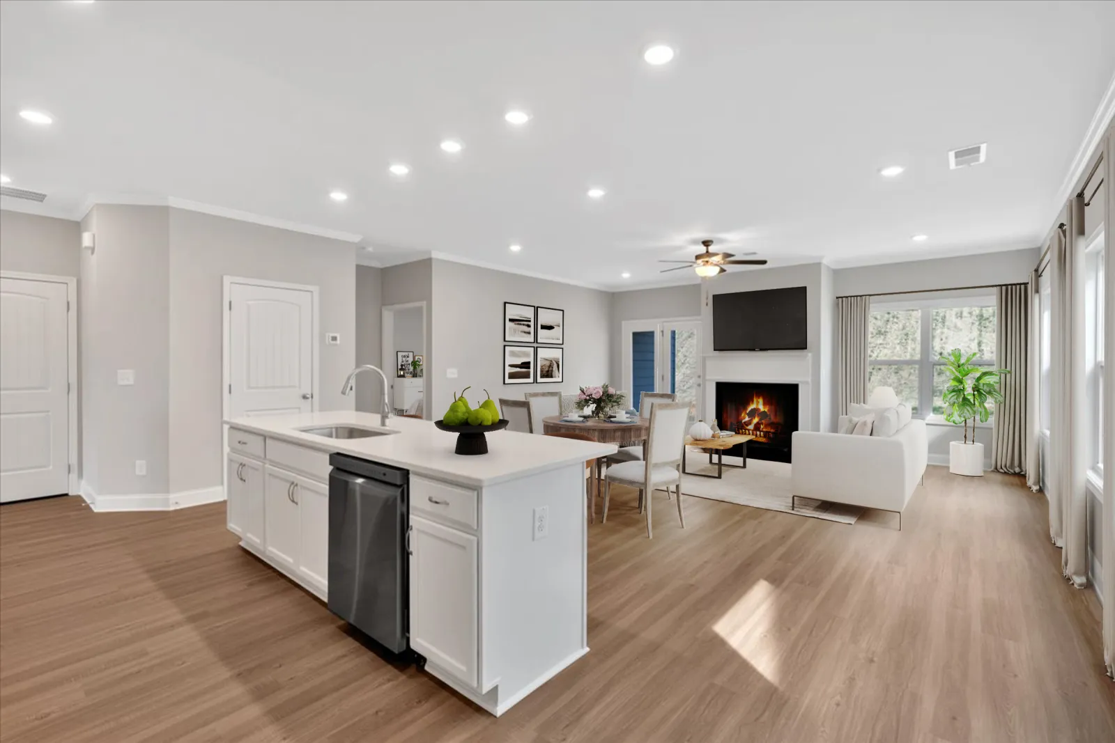 Open living space with modern kitchen island, dining area, and cozy living room with fireplace and TV.