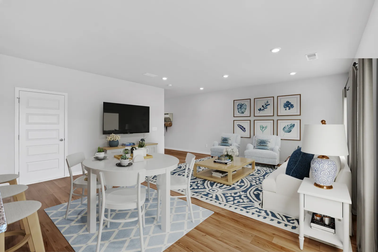 Bright modern living room with dining area, white furniture, and blue accents on decor and rug.