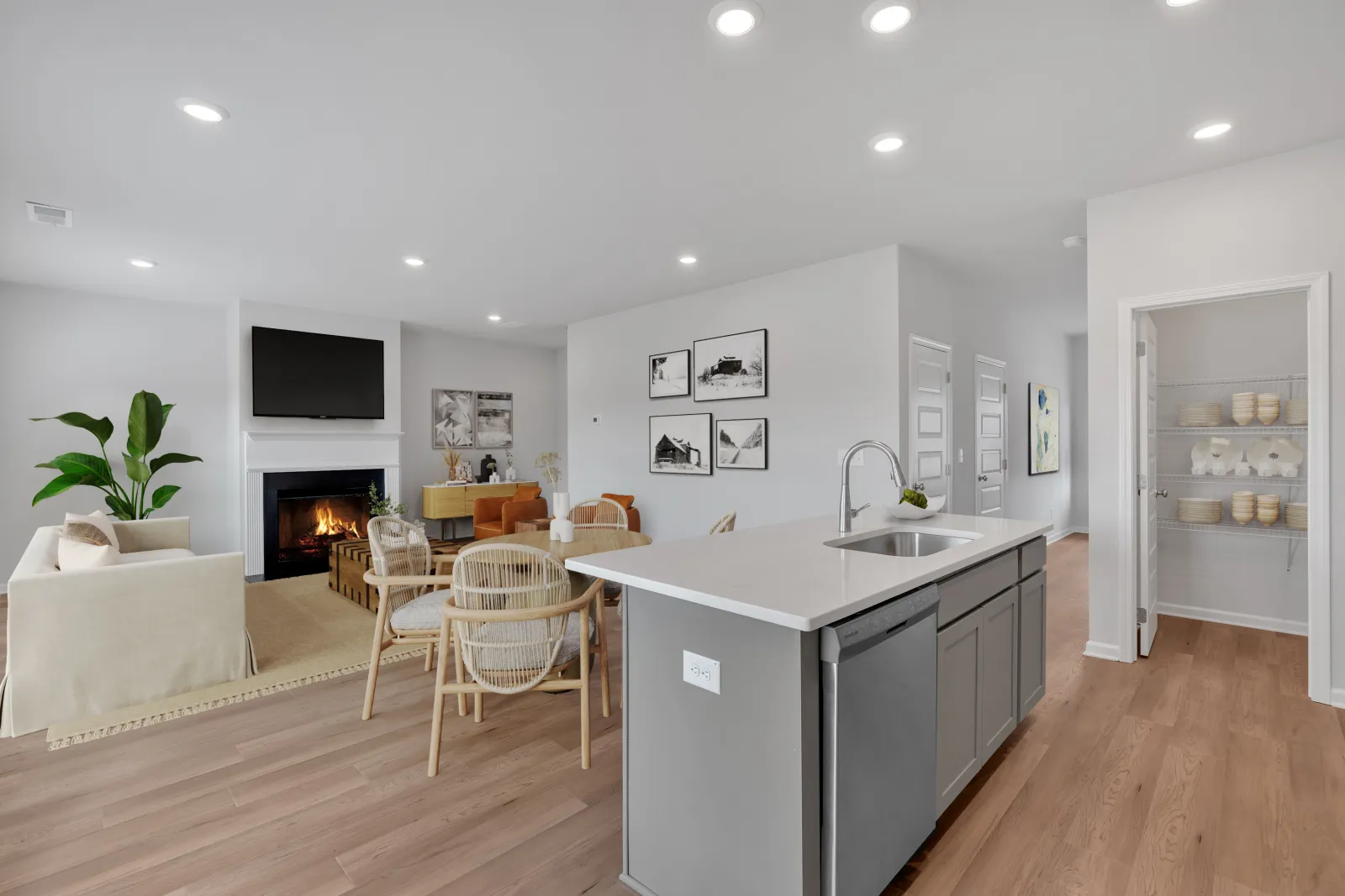 Open concept living room and kitchen with fireplace, modern furniture, wood flooring, and walk-in pantry.
