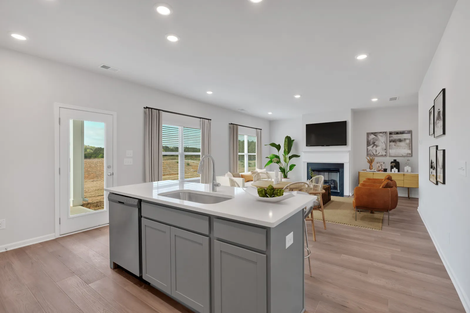 Modern open-concept living room and kitchen with a large island, gray cabinets, and minimalist decor.