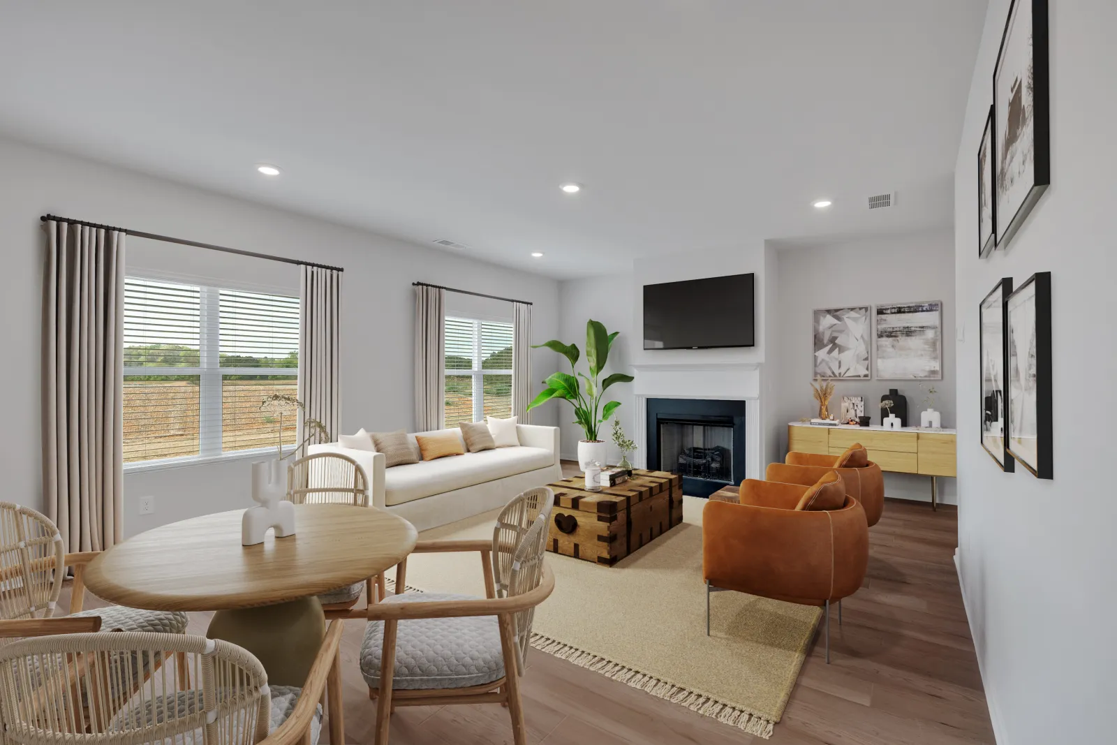 Modern living room with beige sofa, brown armchairs, wooden dining table, and TV above fireplace, bright with natural light