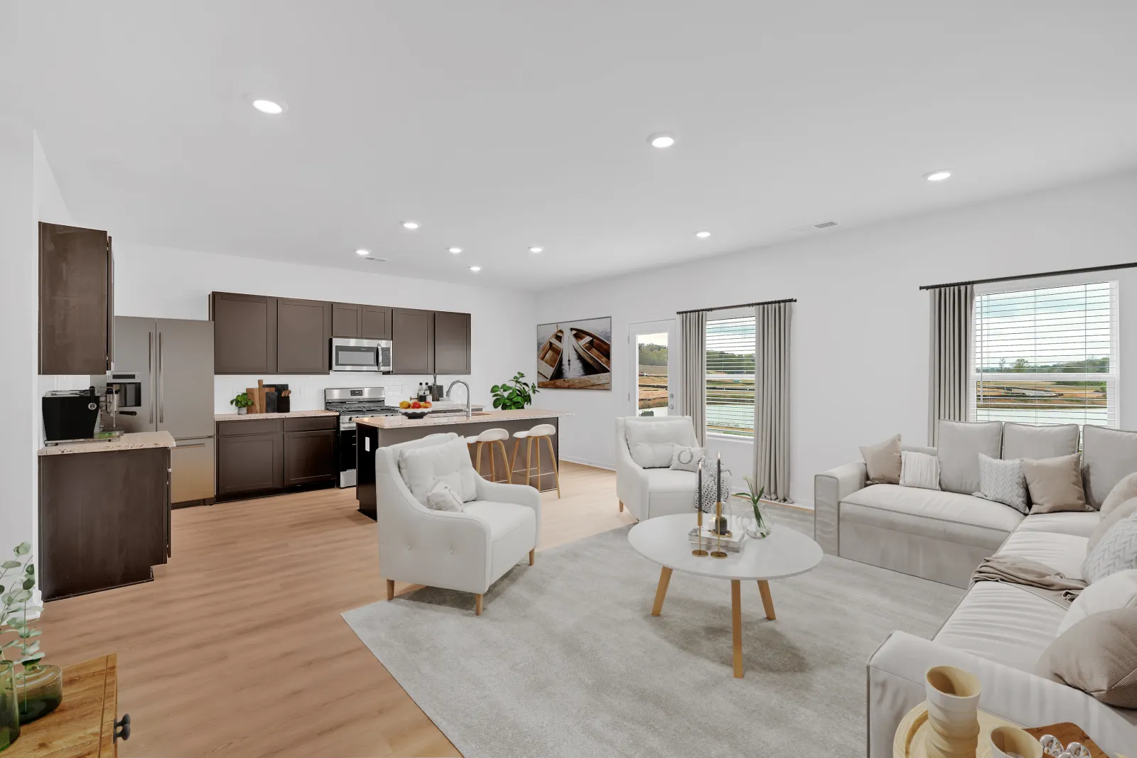 Modern open-concept living room and kitchen with neutral tones, white furniture, wooden flooring, and large windows.