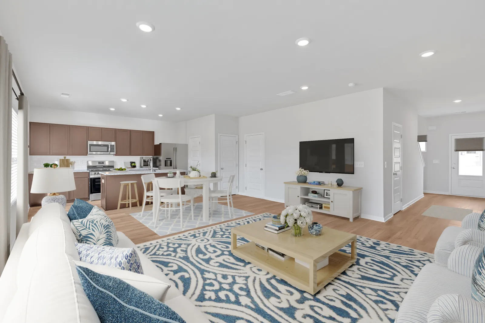 Modern living room featuring stylish furniture, light colors, and open layout with kitchen view.