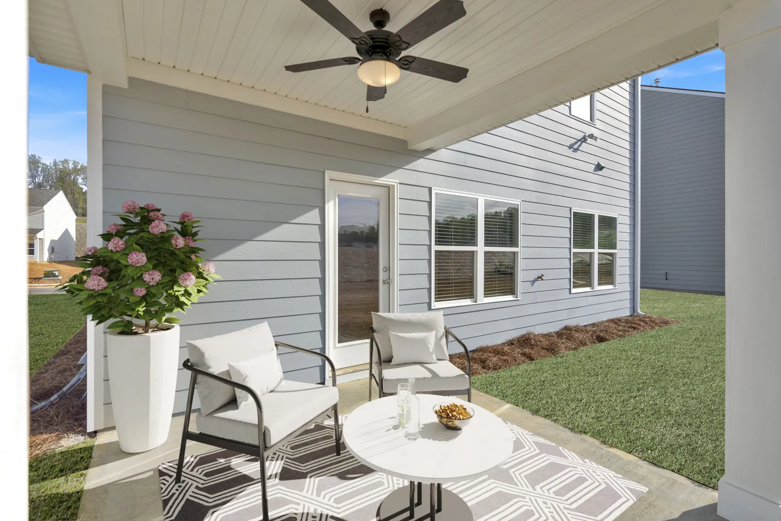 A stylish outdoor patio with modern seating, plants, and a table, perfect for relaxation.