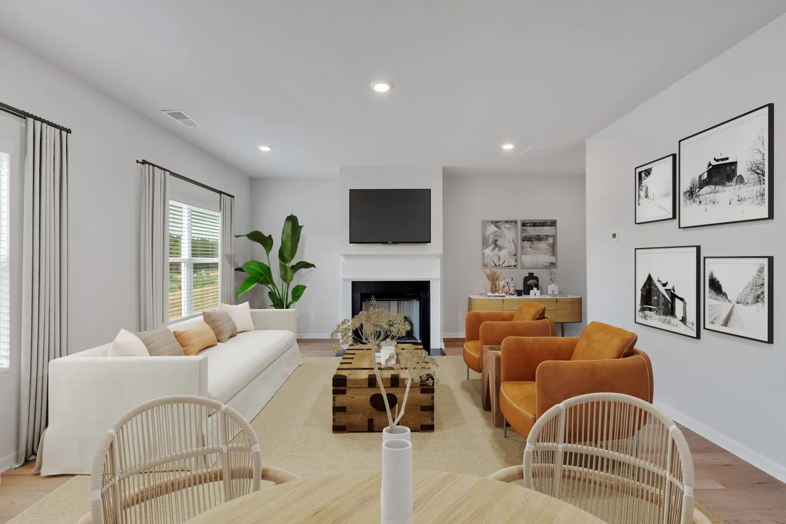 Modern living room with white sofa, brown armchairs, wooden coffee table, fireplace, and black and white wall art.