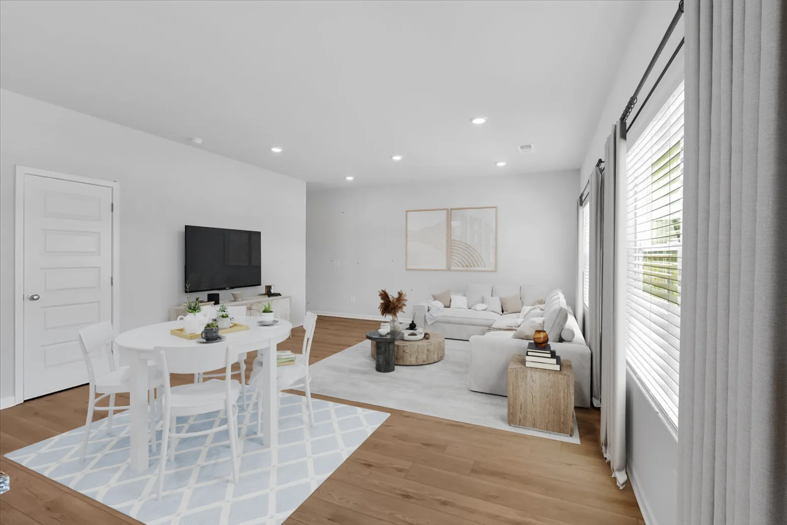 Bright modern living room with white furniture, wooden flooring, round dining table, and large windows with curtains.