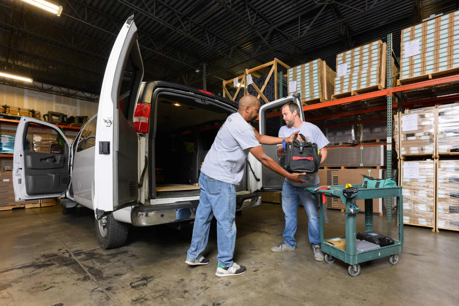 a couple of men standing next to a van in a warehouse