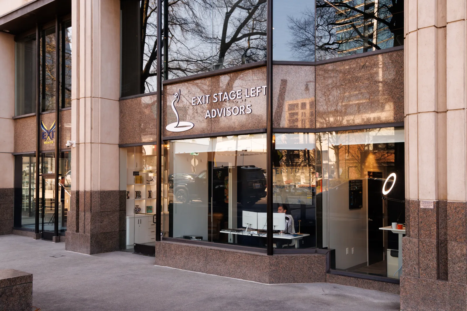 Office building exterior showing Exit Stage Left Advisors with large glass windows and granite facade.