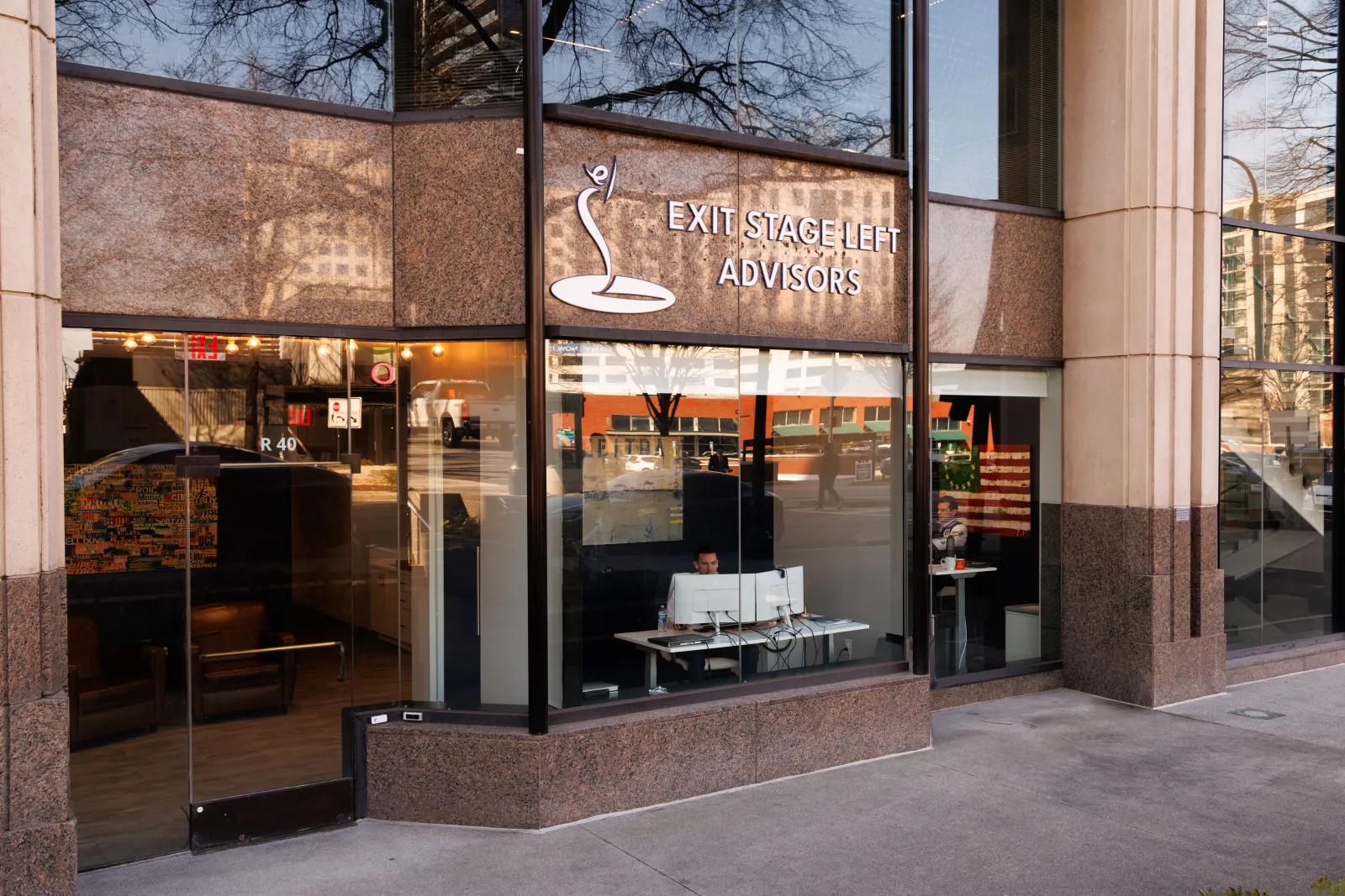 Street view of Exit Stage Left Advisors office with large glass windows and a person working inside.