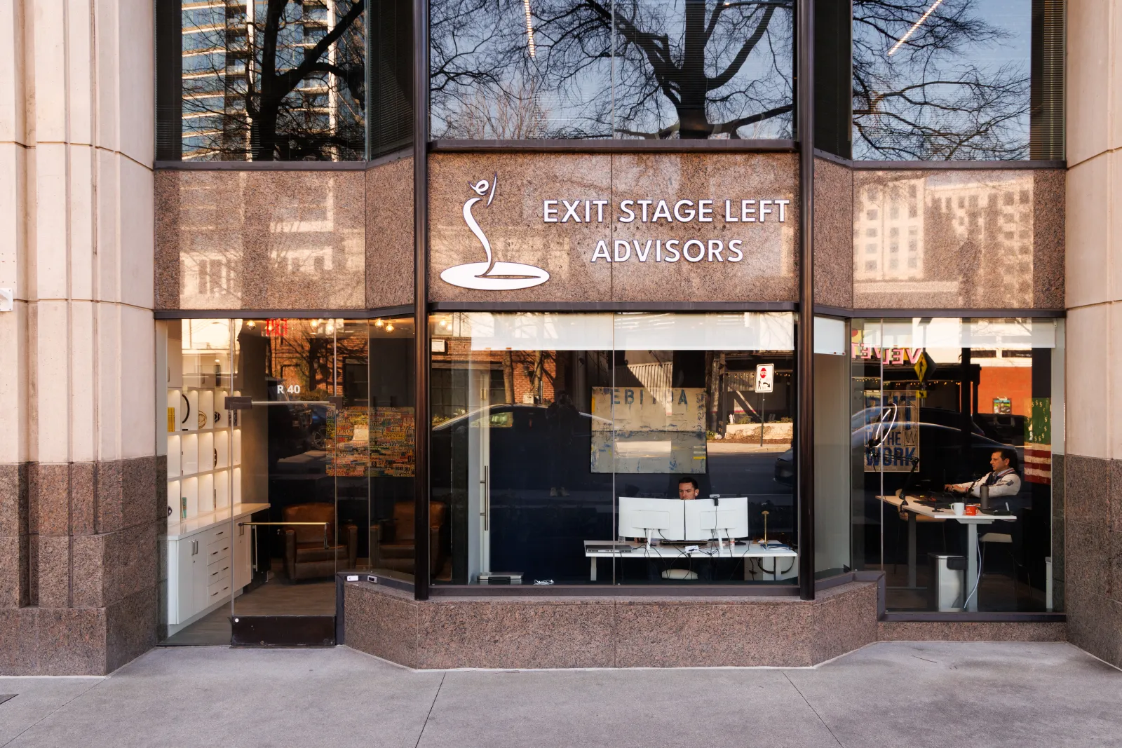 Office front of Exit Stage Left Advisors with large windows and two people working inside at desks.