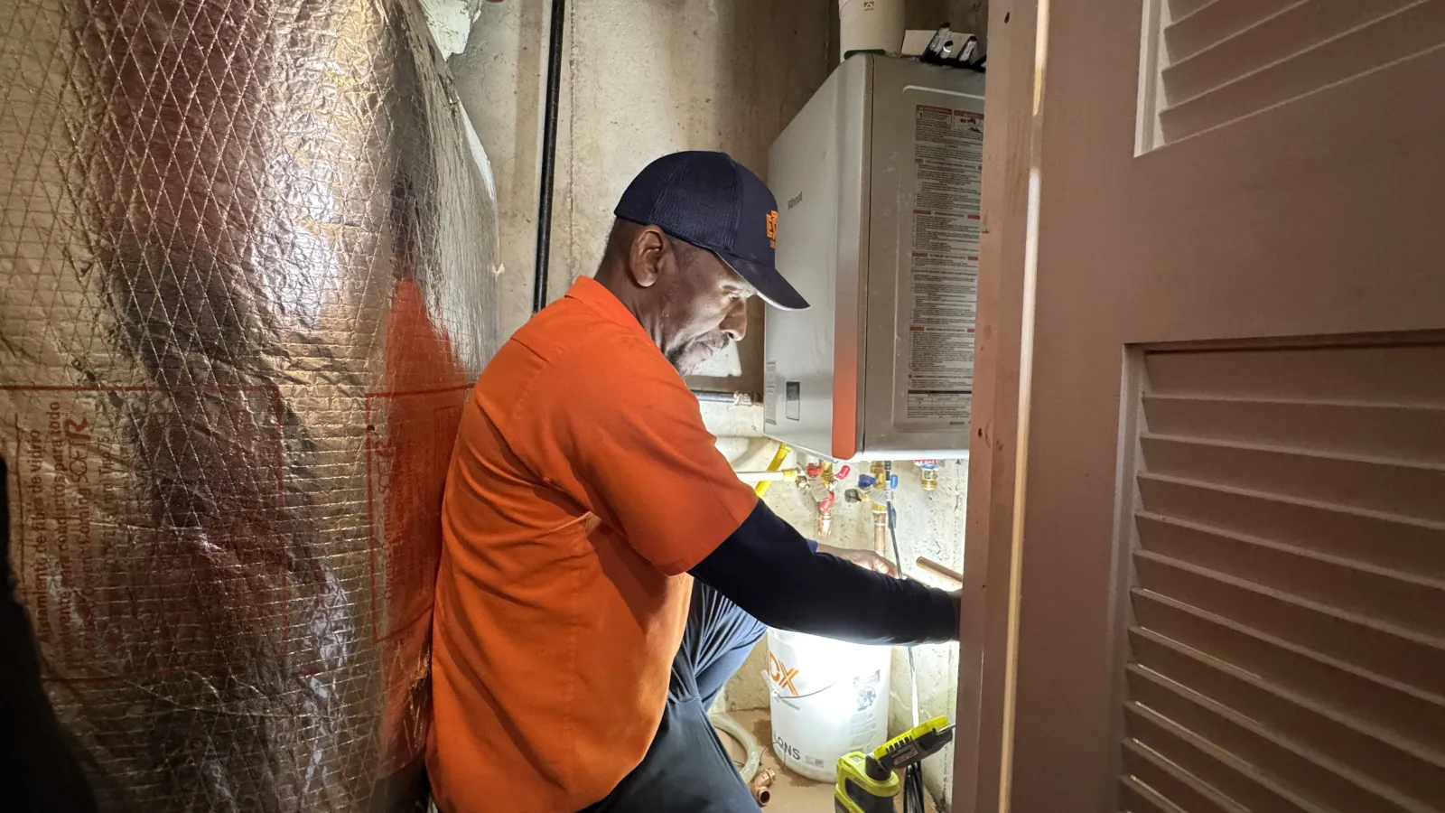 Estes Services installing a water heater in a basement. Estes Plumber wearing his Estes Unifrom
