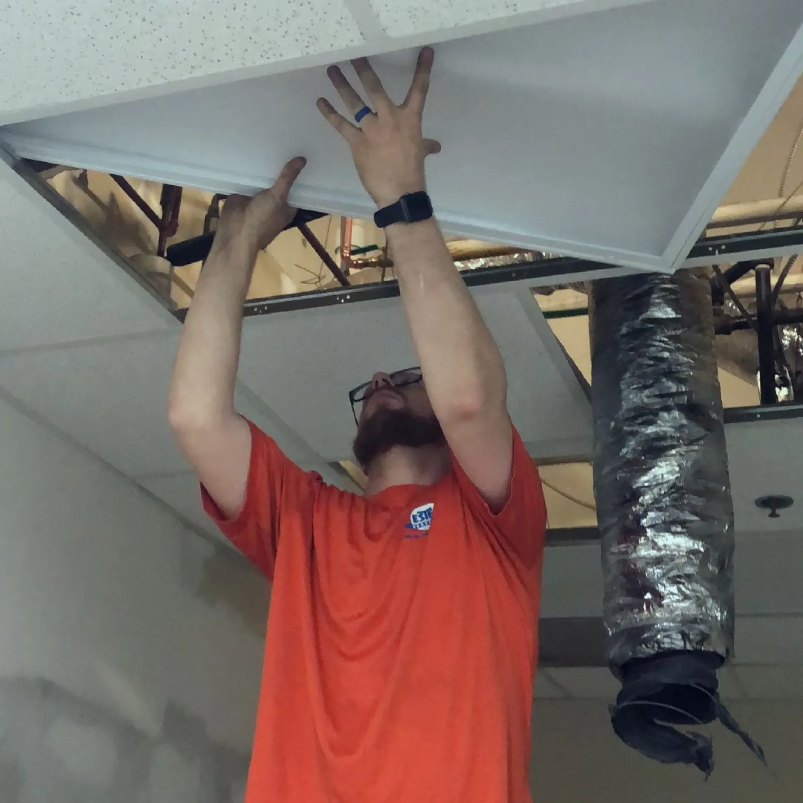Estes Electrician  in an orange uniform installing a new wiring system