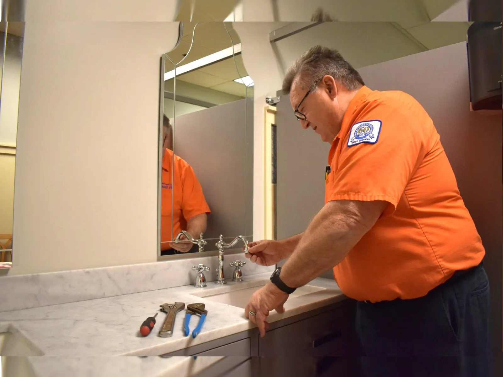 Estes Services Plumber is fixing a faucet in a bathroom
