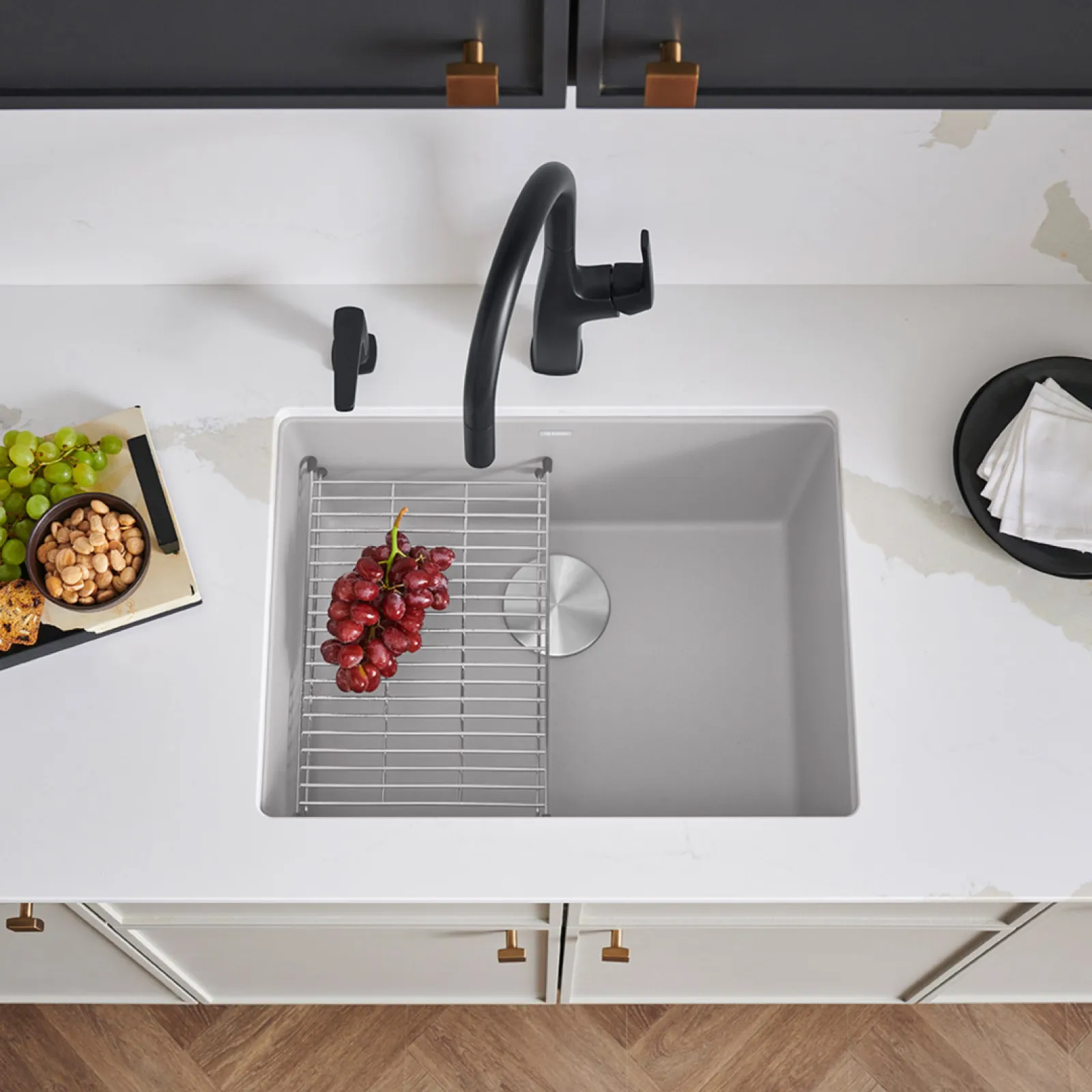 a white kitchen sink with a black handle and a black handle