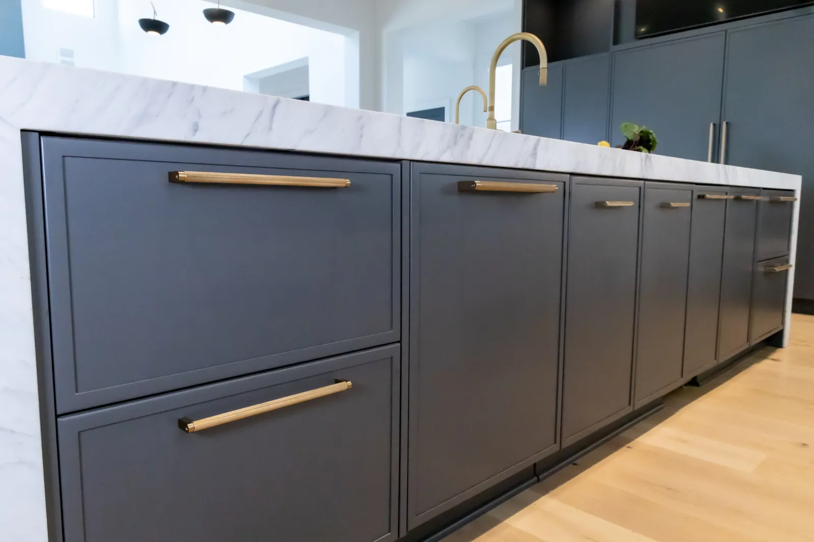 Modern kitchen featuring dark cabinetry and a marble countertop with stylish gold hardware.
