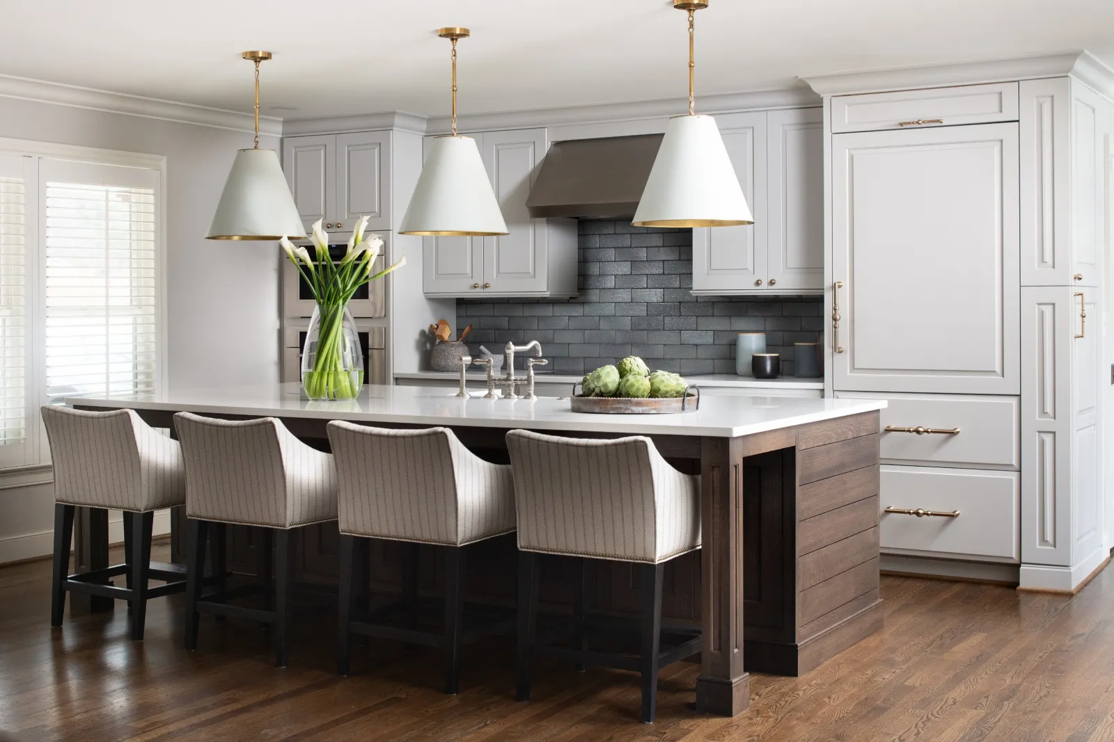 Modern kitchen with a large island, stylish bar stools, and elegant lighting fixtures.
