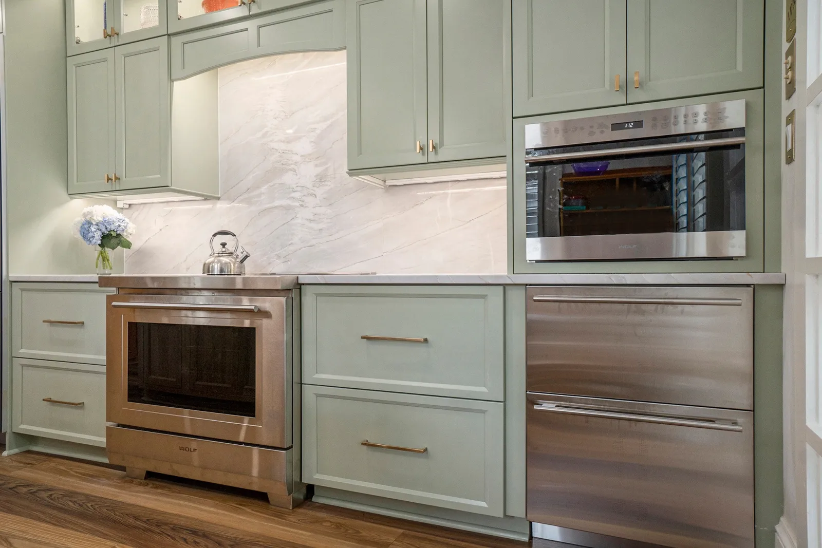 Modern kitchen with green cabinetry, stainless steel appliances, and sleek countertop design.
