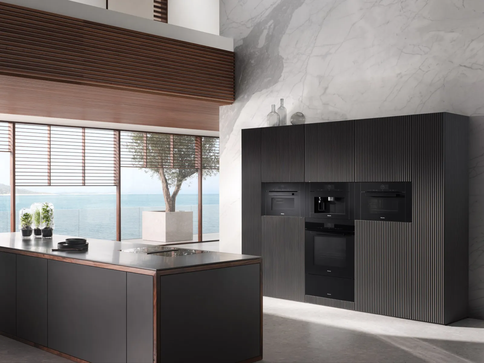 Modern black kitchen featuring sleek cabinets, marble walls, and ocean view windows.