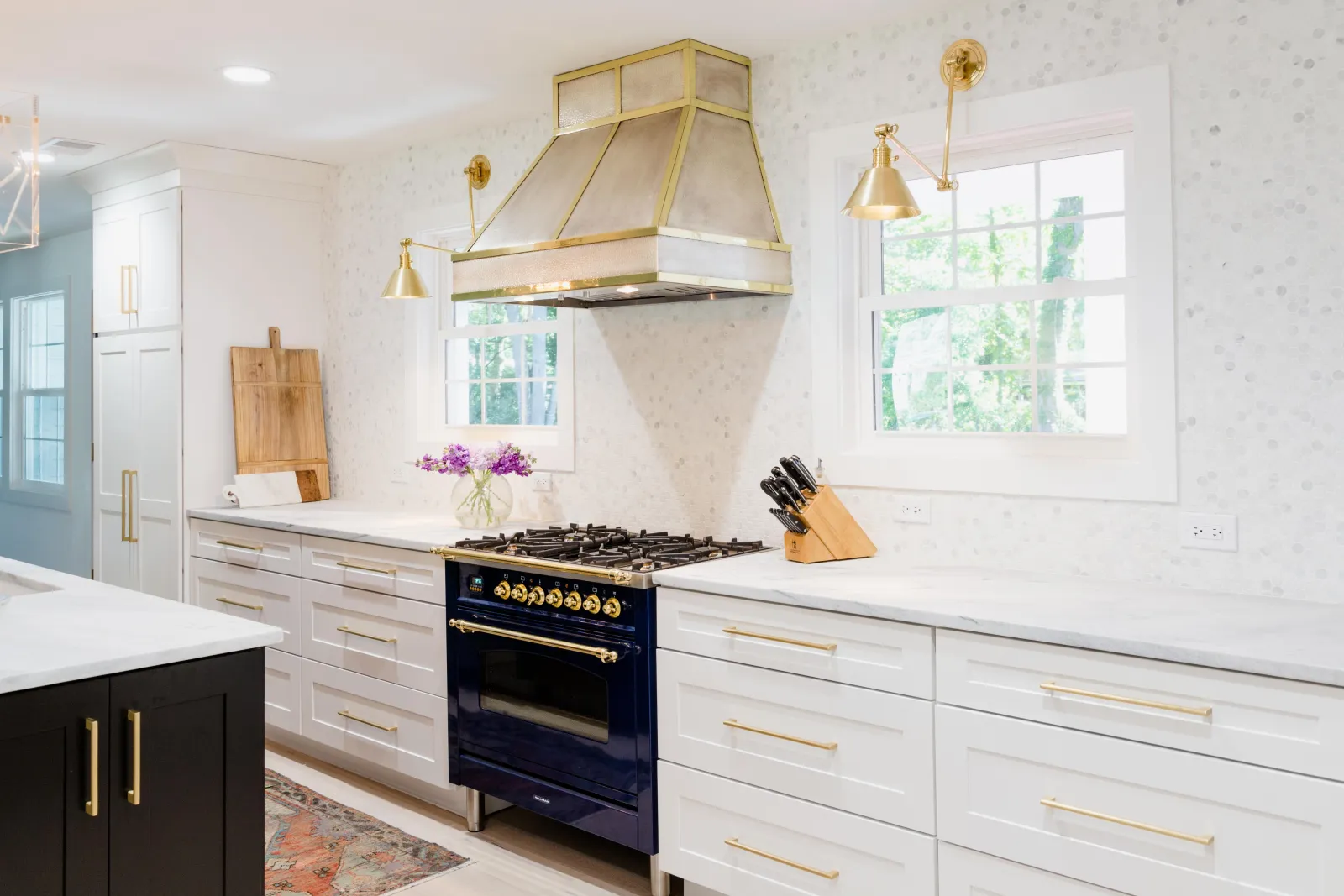 Modern kitchen featuring a blue stove, white cabinetry, and stylish gold accents.