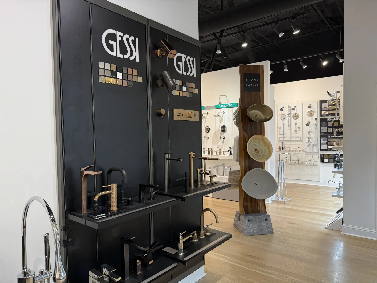 Showroom display of modern Gessi faucets and fixtures in various metals with design samples and lighting.