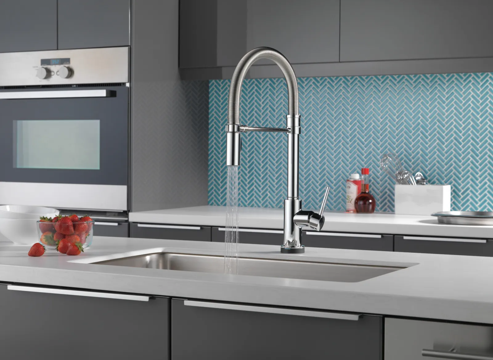 Modern kitchen with a stylish faucet, stainless steel sink, and vibrant aqua herringbone backsplash.