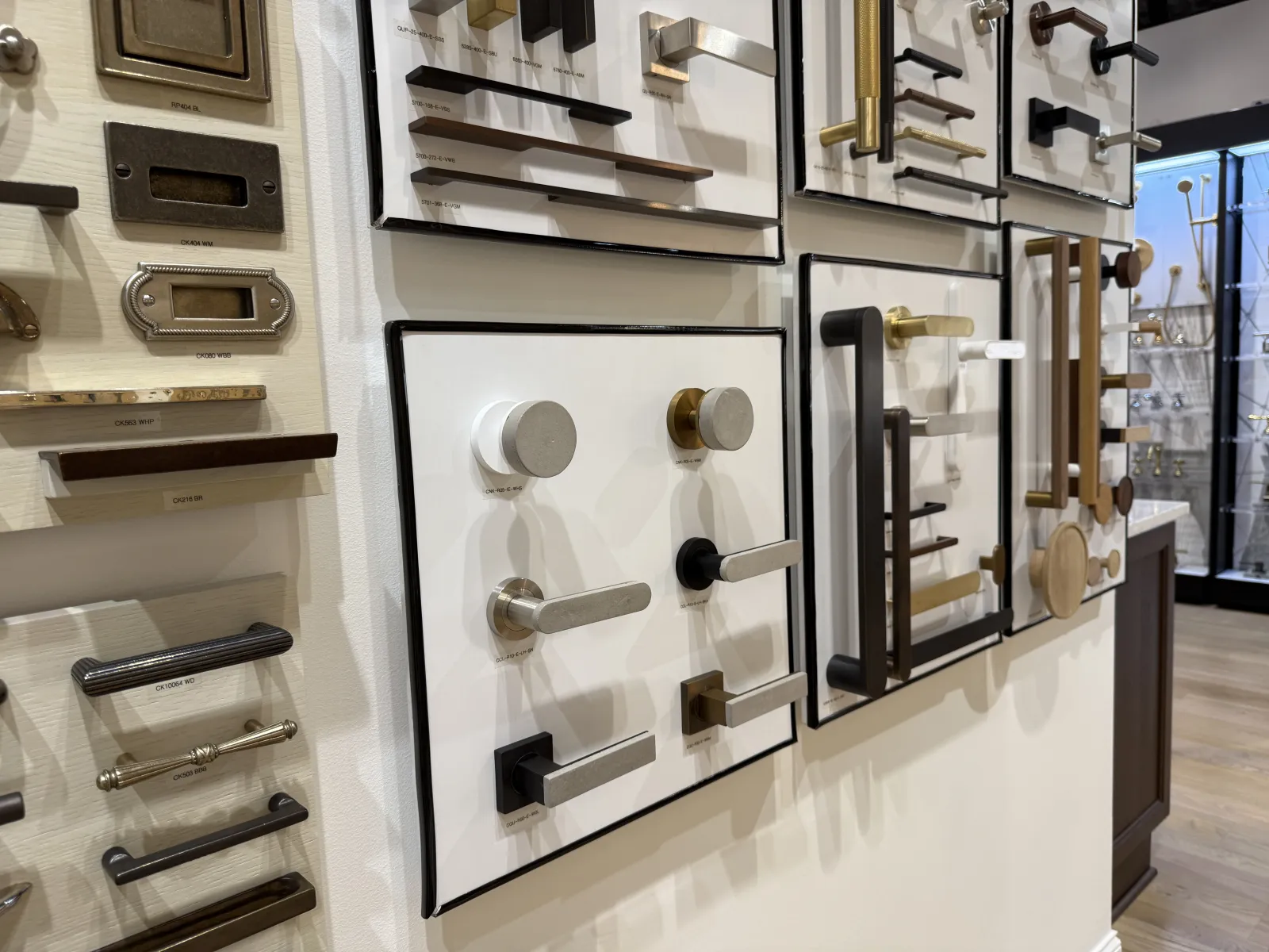 Assorted modern and classic door handles and knobs displayed on white panels in a showroom