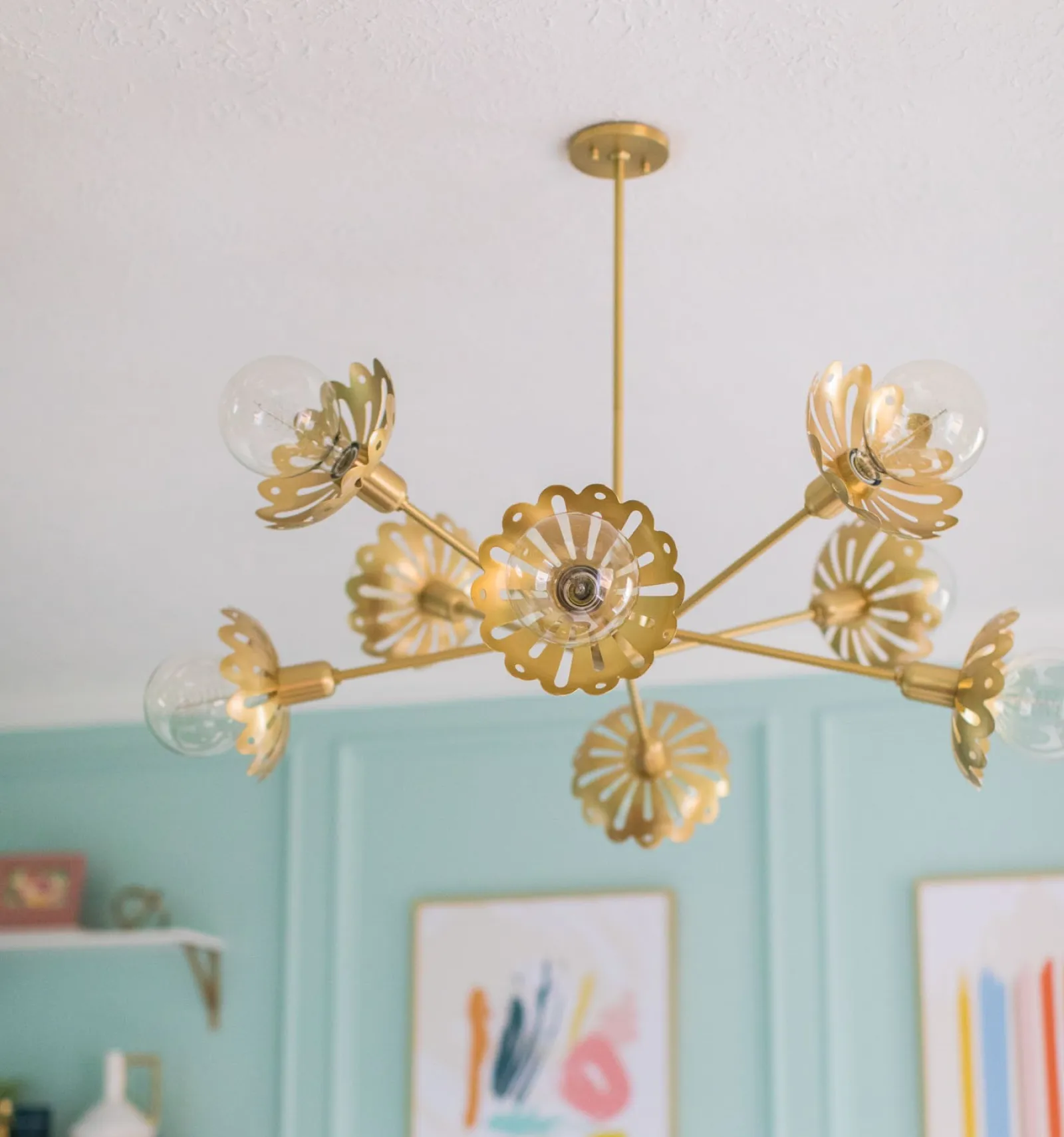 Stylish gold chandelier with floral design and glass bulbs, enhancing a bright, modern interior.