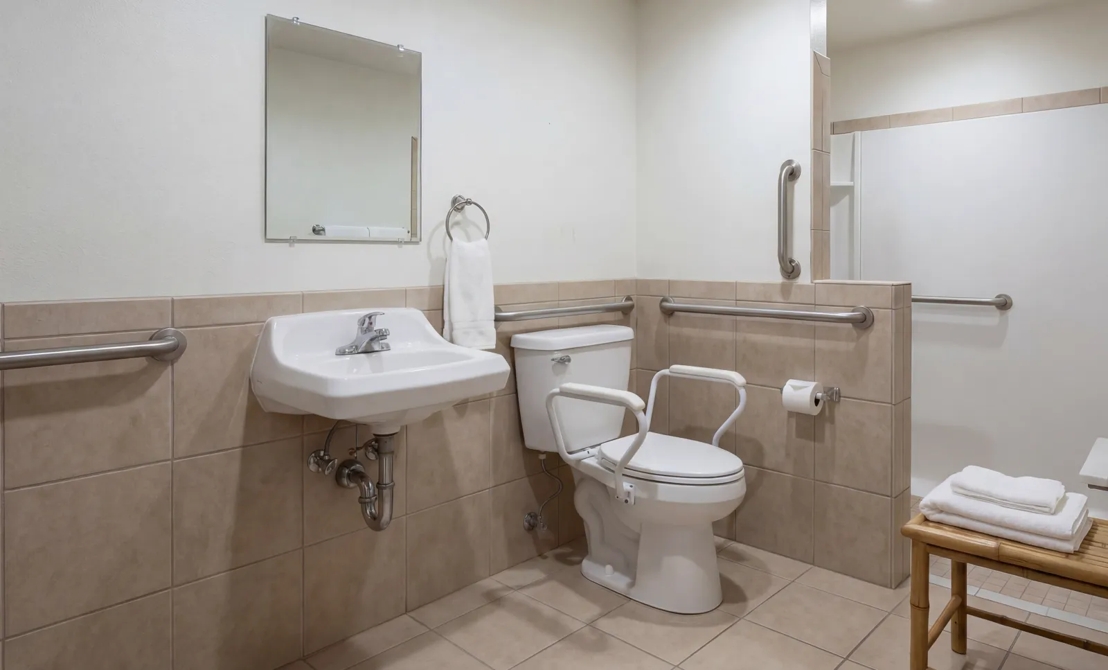 Accessible bathroom with safety rails, wall-mounted sink, toilet with support arms, and a walk-in shower with grab bars.