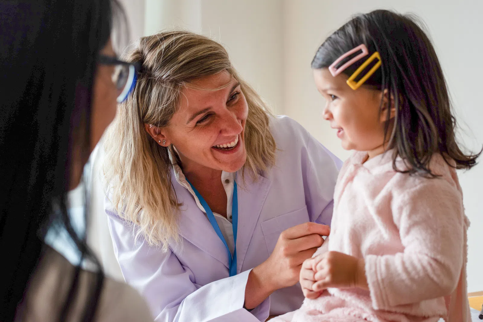 Smiling female doctor interacts with young girl patient during a friendly medical check-up in clinic.