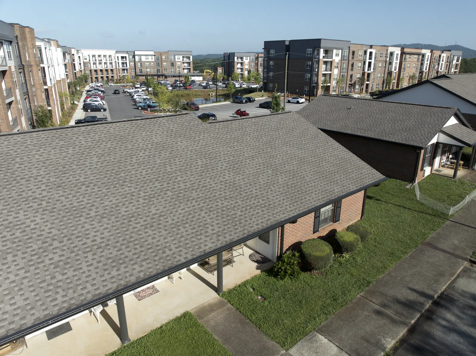 Aerial view of a residential area with brick houses, large parking lot, and modern apartment buildings in the background
