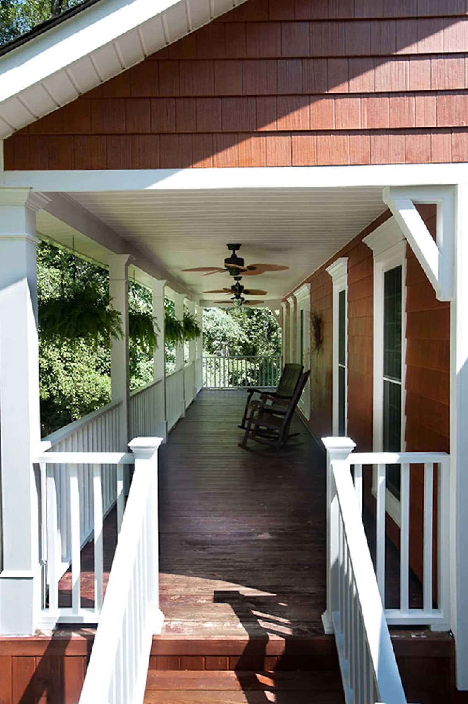 a porch with a wood railing and a wood deck with a chair and a wood railing and a