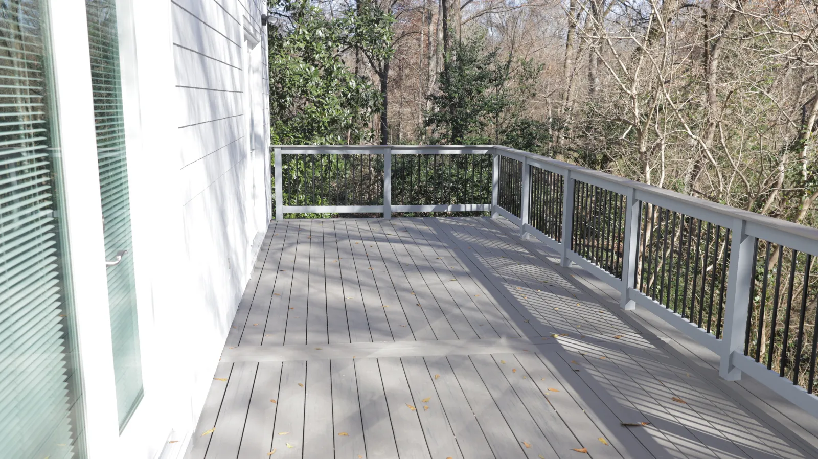 a wooden deck with a railing and trees on the side