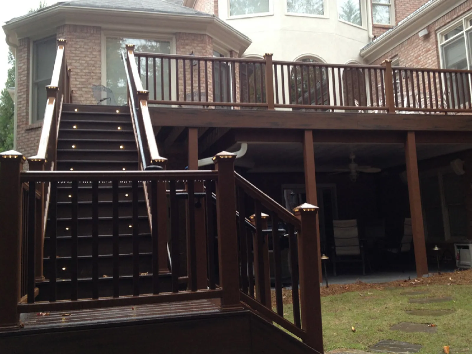 a deck with a railing and a house in the background
