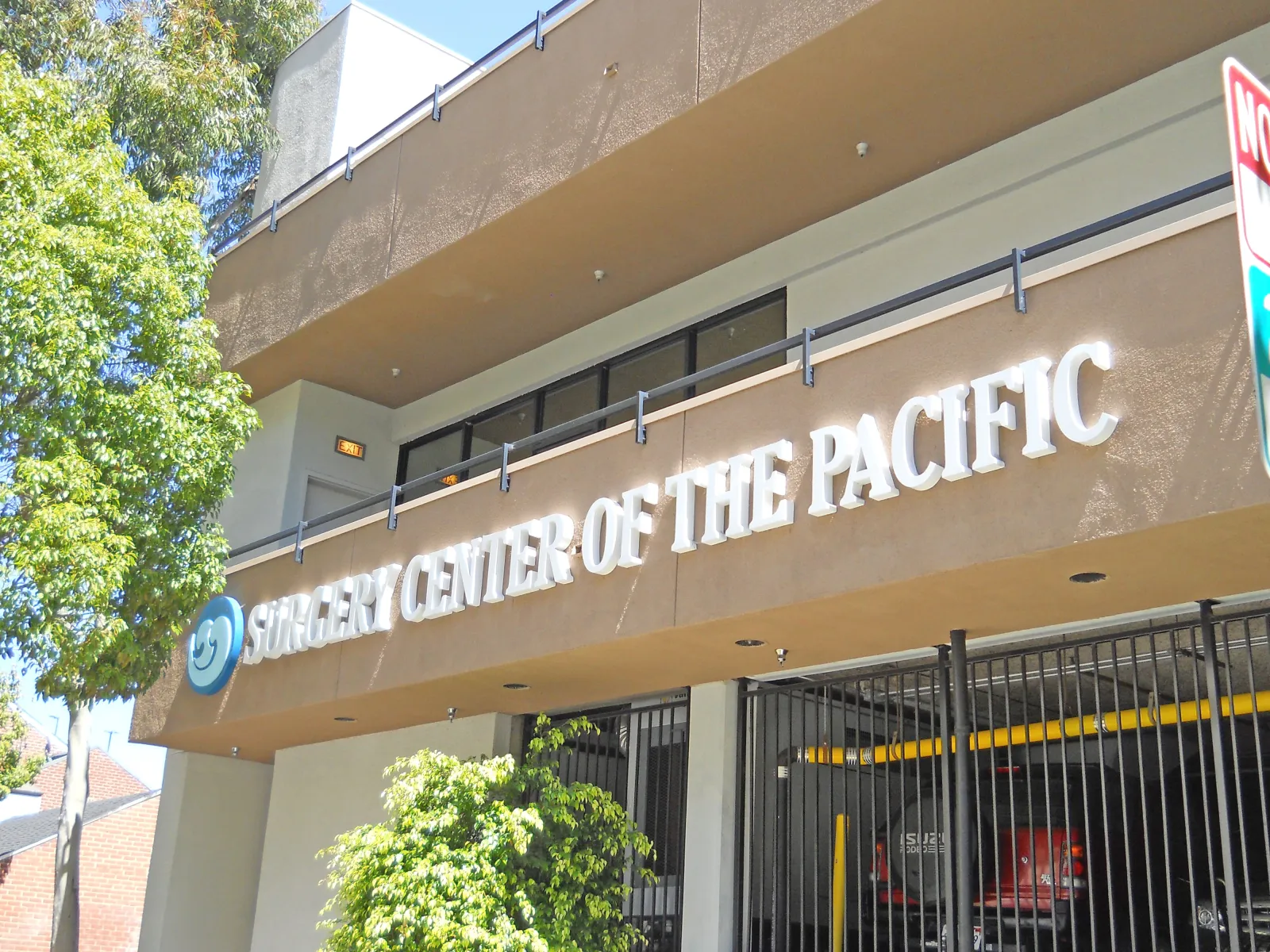 Exterior of Surgery Center of the Pacific building with signage and surrounding greenery on a sunny day.