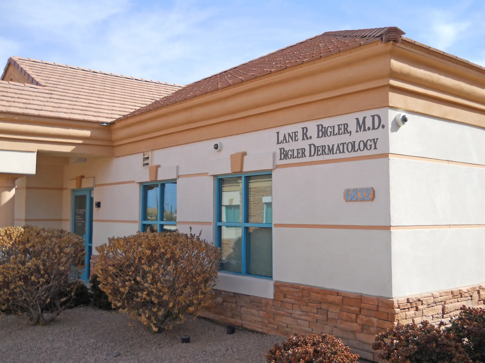Exterior view of Lane R. Bigler M.D. Dermatology office building with beige walls and blue windows.