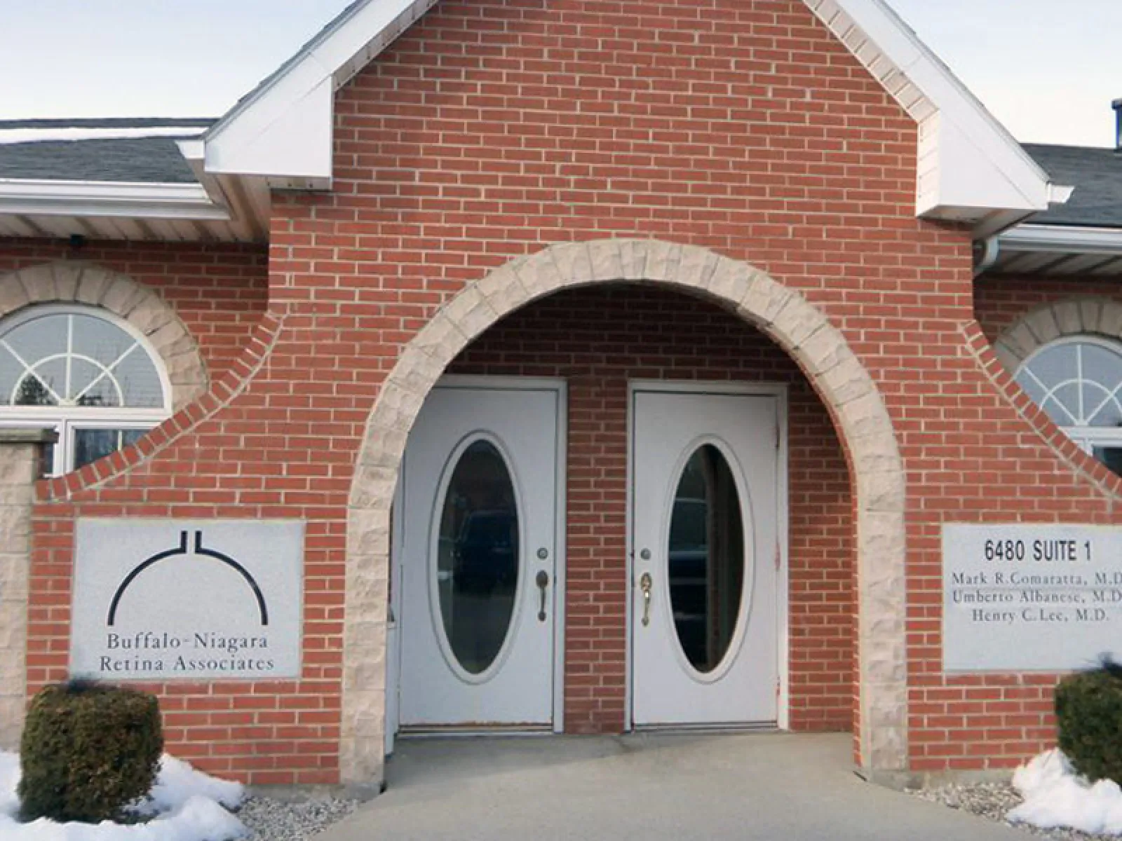 Brick building entrance with double oval glass doors and Buffalo-Niagara Retina Associates signage.