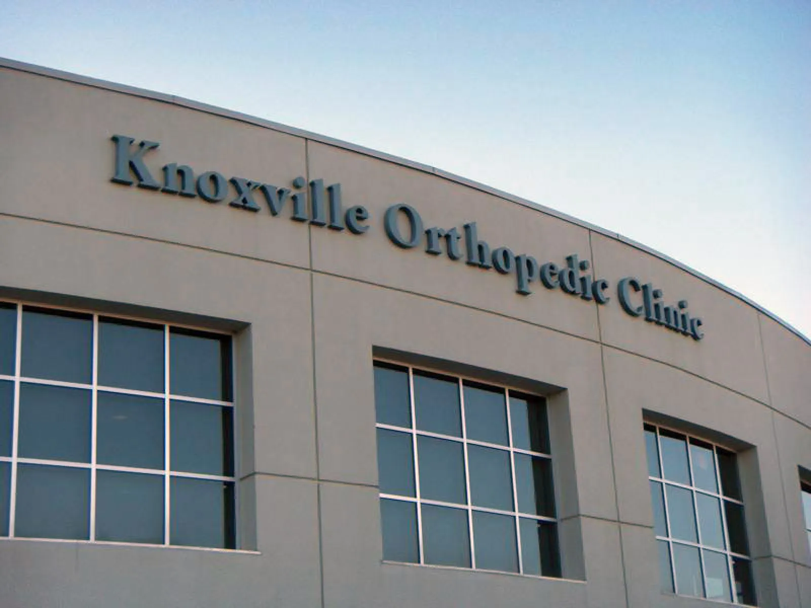 Exterior of Knoxville Orthopedic Clinic building with large windows under a clear sky.