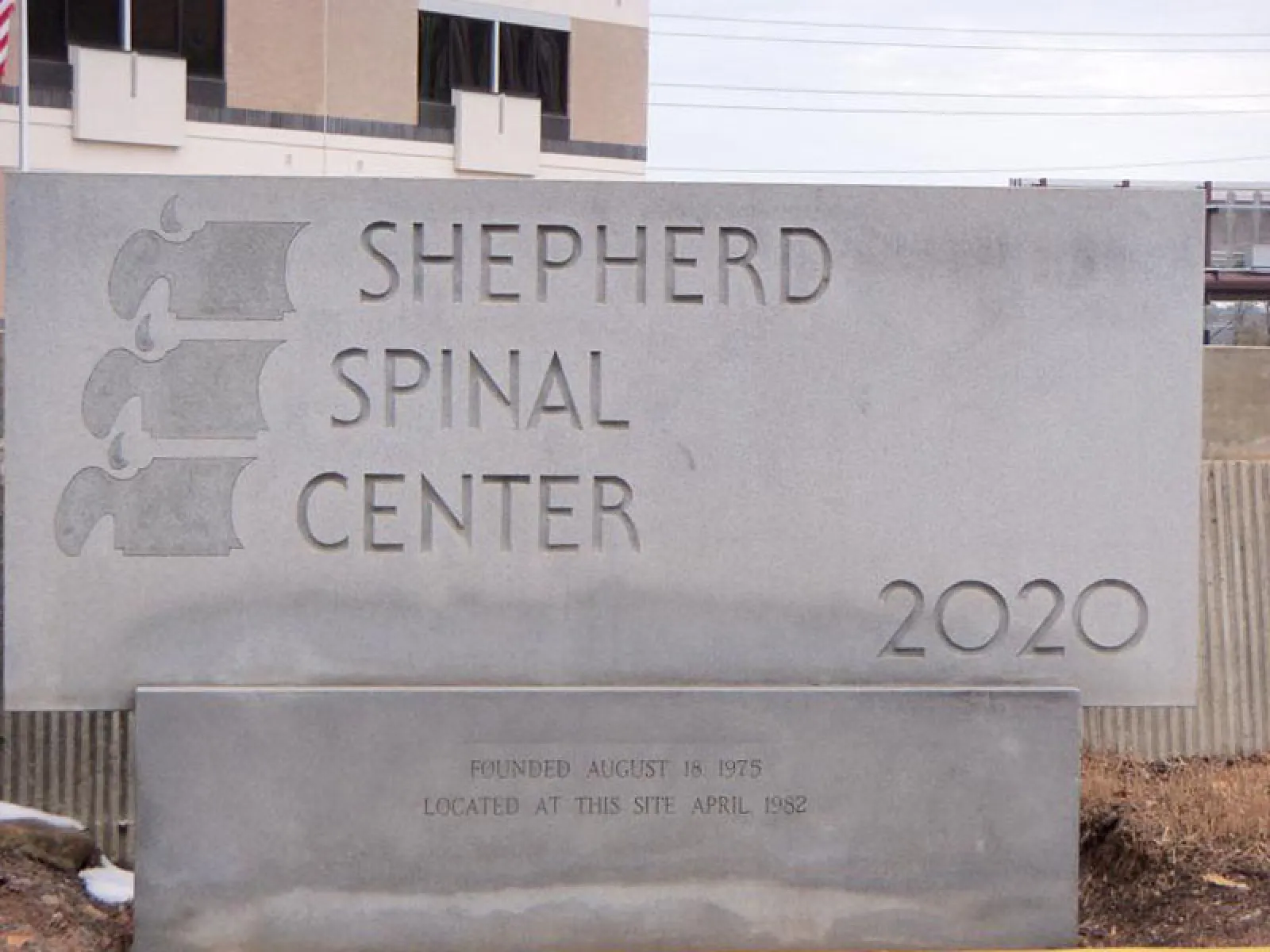 Stone sign for Shepherd Spinal Center with logo and founding dates outside a building.